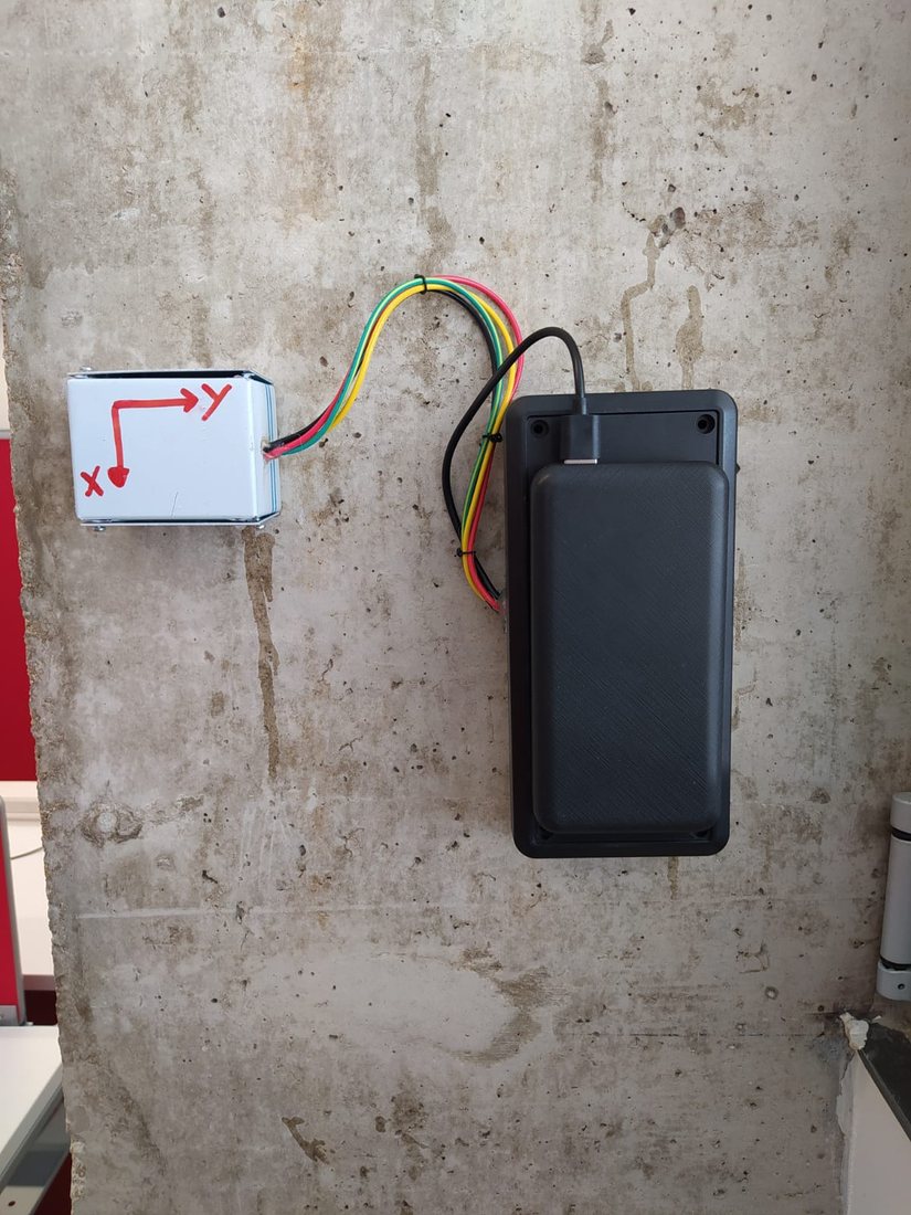 Sensor and battery pack fixed to a concrete wall for continuous tilt monitoring.